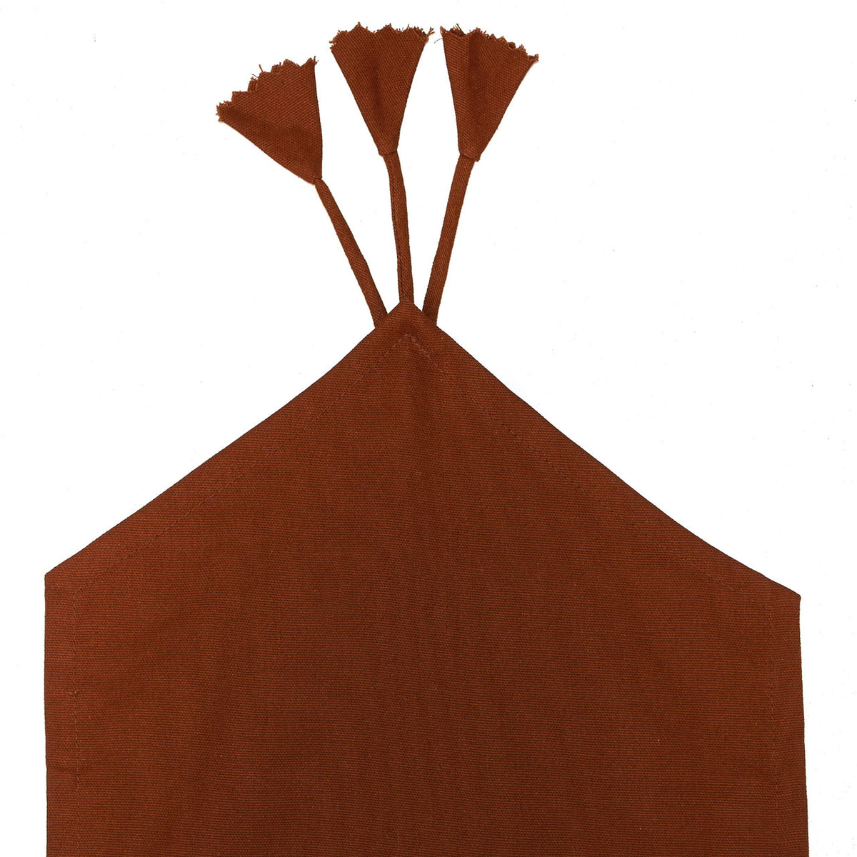 Close-up of the brown reverse fabric, stitched corner and tassel fringe on the In-Sattva green table runner