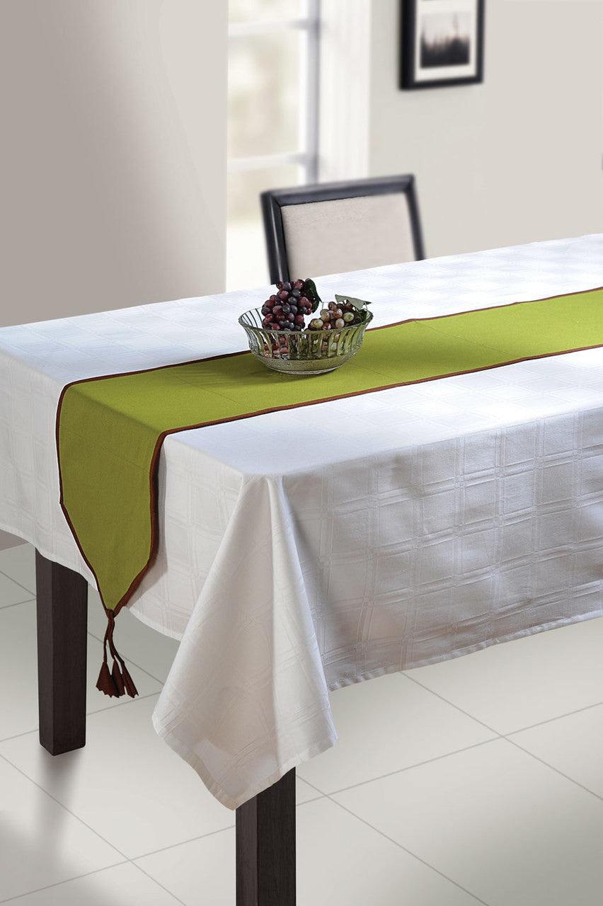 In-Sattva green solid cotton table runner with contrast trim and tassel fringe styled on a white table