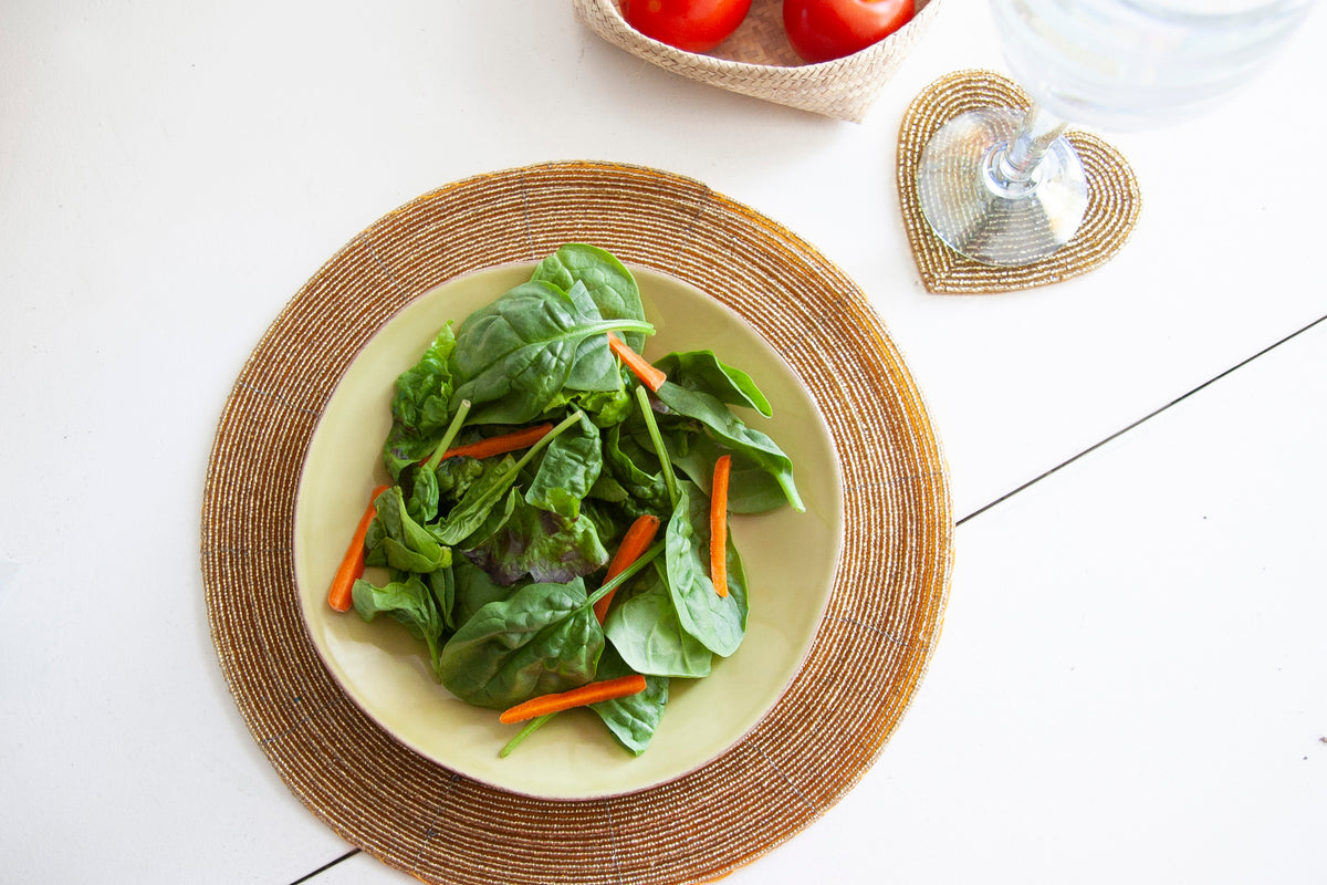 Overhead dining setting with a salad plate on an In-Sattva gold glass beaded placemat