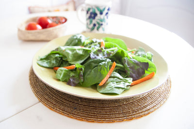 Salad plate displayed on an In-Sattva gold handmade glass beaded round placemat