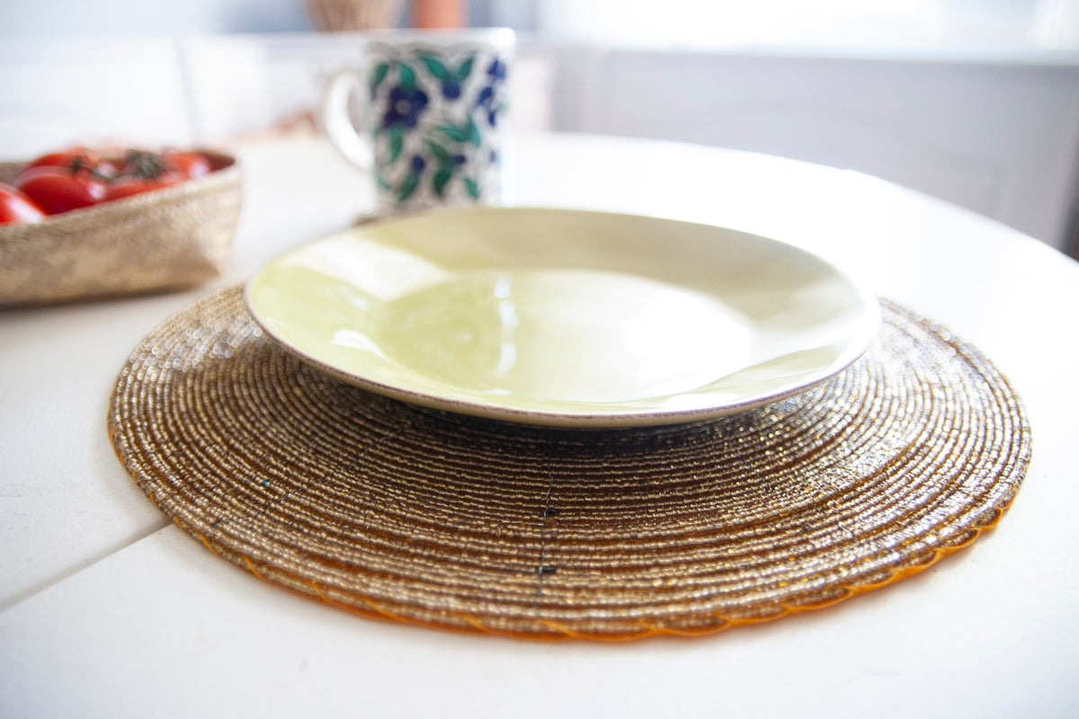 Empty dinner plate styled on an In-Sattva gold handmade glass beaded round placemat