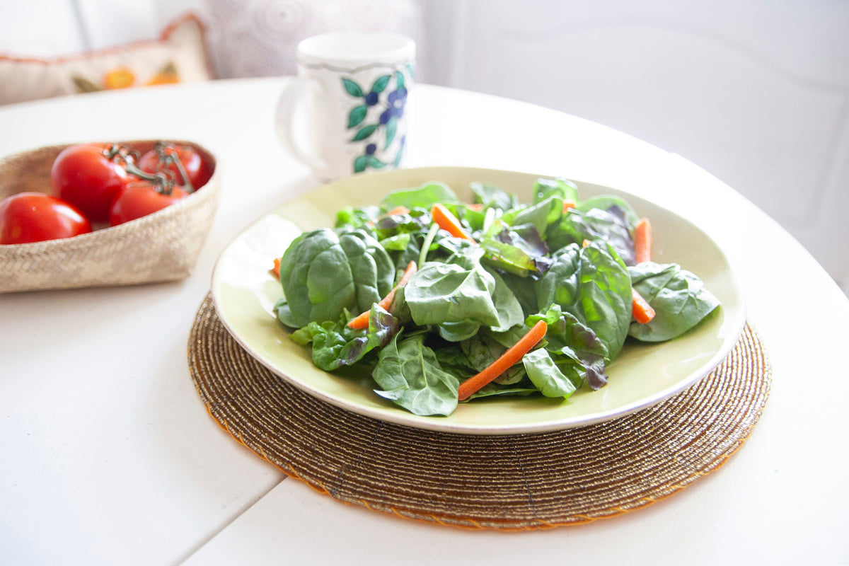 Dining table styled with a salad plate on an In-Sattva gold glass beaded round placemat