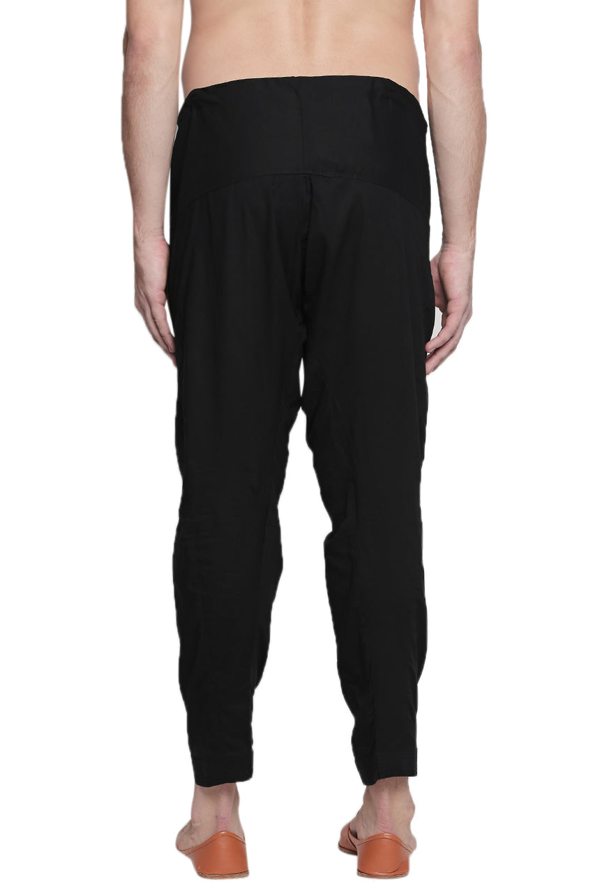 Back view of In-Sattva men's black cotton baggy salwar yoga pants, showing the roomy seat and tapered-leg shape from the back.