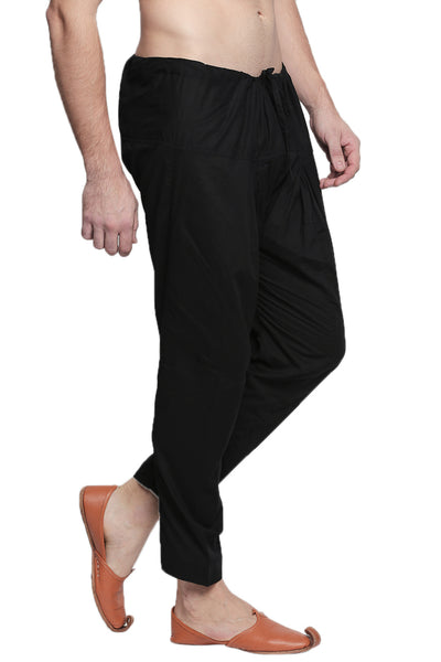 Right profile view of In-Sattva men's black cotton baggy salwar yoga pants, showing the baggy hip shape narrowing into the tapered ankle.