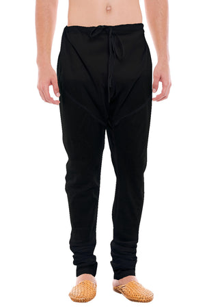 Front view of In-Sattva men's black cotton churidar pants, showing the drawstring waist, tapered legs and ankle gathers.