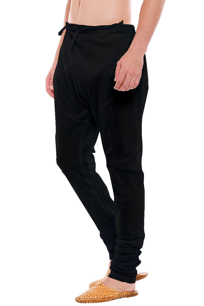 Left profile view of In-Sattva men's black cotton churidar pants, showing the smooth cotton profile and gathered ankle fit.
