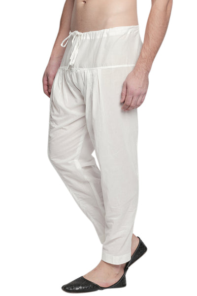 Left profile view of In-Sattva men's off-white cotton baggy salwar yoga pants, showing the baggy hip shape narrowing into the tapered ankle.