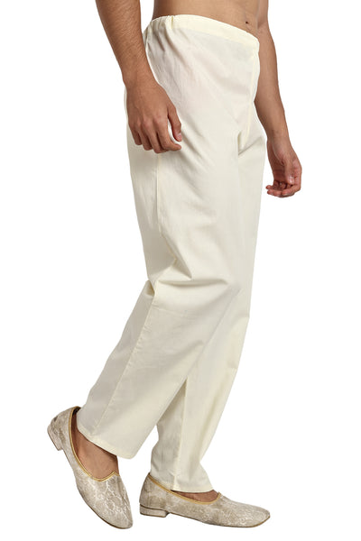 Left profile view of In-Sattva men's off-white cotton drawstring lounge pants, showing the full-length relaxed silhouette and straight-leg drape.