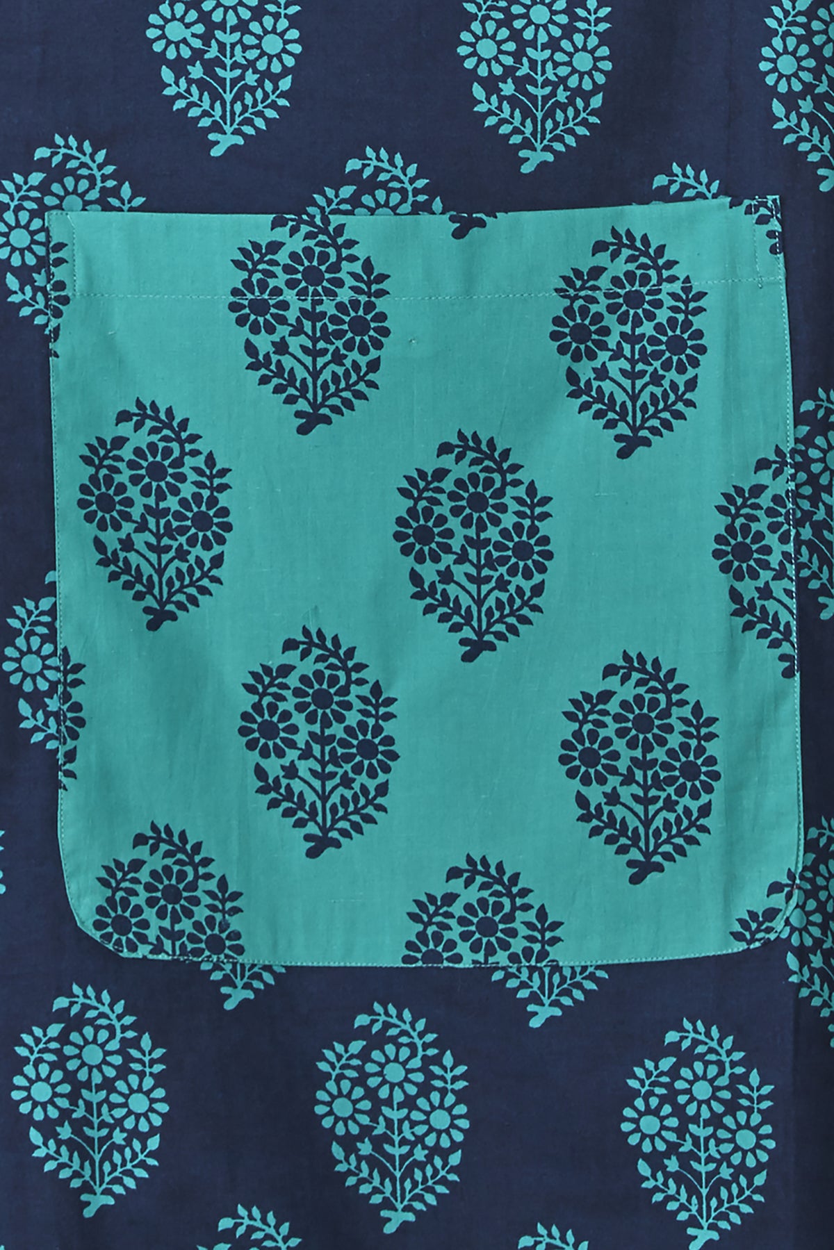 Close-up of the multicolor bohemian print, roomy pocket and frilly hem on an In-Sattva cotton apron