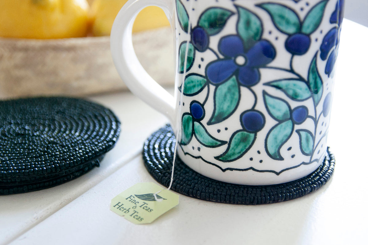 Close-up of a floral coffee mug on a Rangeene black glass beaded round coaster