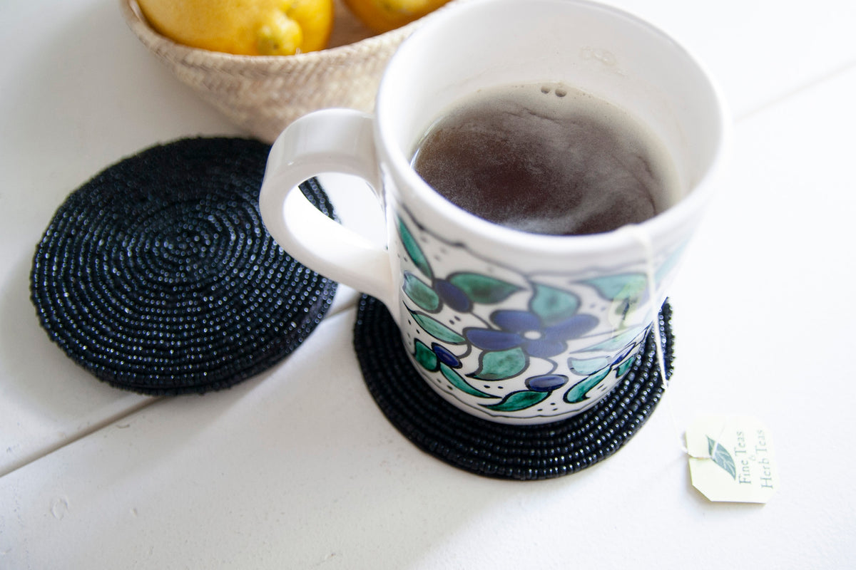 Top view of a floral coffee mug on a Rangeene black glass beaded round coaster