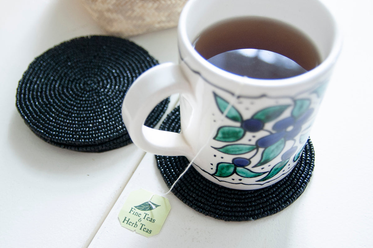 Rangeene black glass beaded round coaster styled with a floral coffee mug