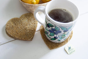Rangeene gold glass beaded heart shaped coaster styled with a floral coffee mug