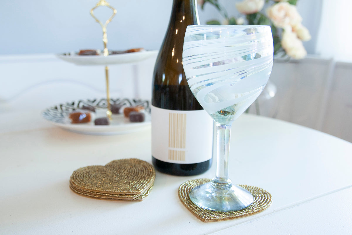 Rangeene gold glass beaded heart shaped coaster styled beneath a wine glass