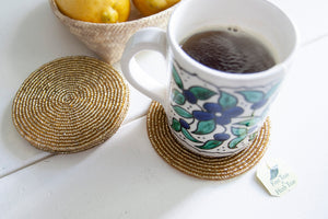 Rangeene gold glass beaded round coaster styled with a floral coffee mug