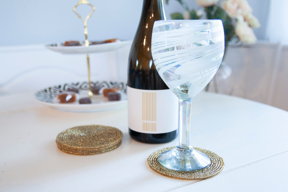 Rangeene gold glass beaded round coaster styled beneath a wine glass