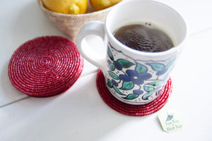 Rangeene red glass beaded round coaster styled with a floral coffee mug
