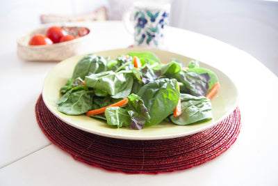 Salad plate displayed on a Rangeene red handmade glass beaded round placemat