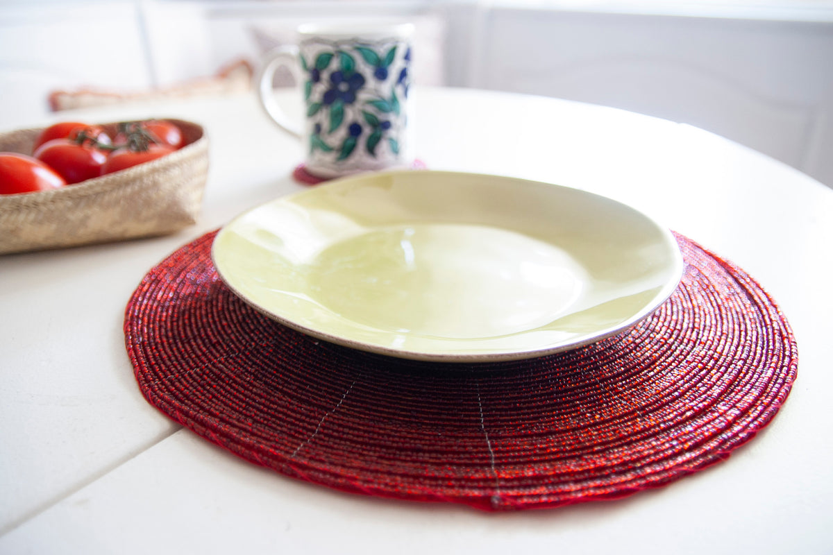Empty dinner plate styled on a Rangeene red handmade glass beaded round placemat