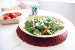 Dining table styled with a salad plate on a Rangeene red glass beaded round placemat