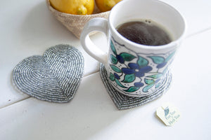 Rangeene silver glass beaded heart shaped coaster styled with a floral coffee mug