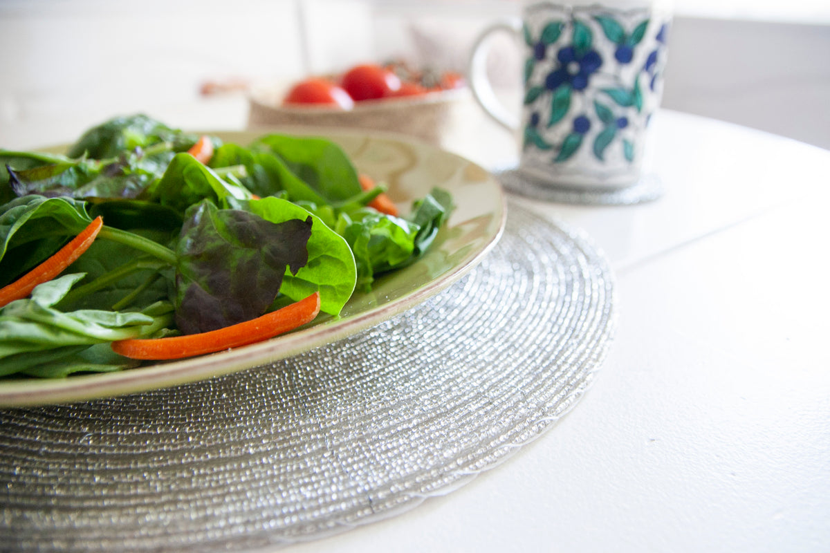 Close-up of silver glass beadwork beneath a salad plate on a Rangeene round placemat