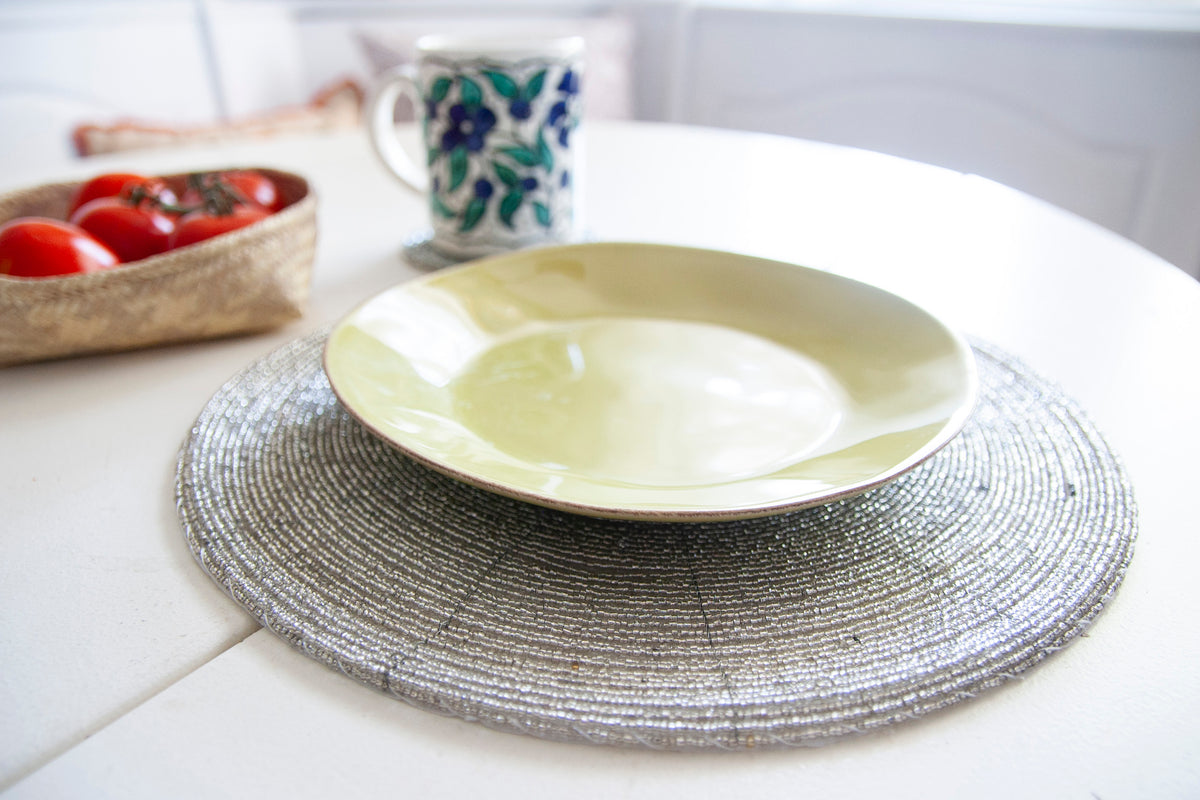 Empty dinner plate styled on a Rangeene silver handmade glass beaded round placemat