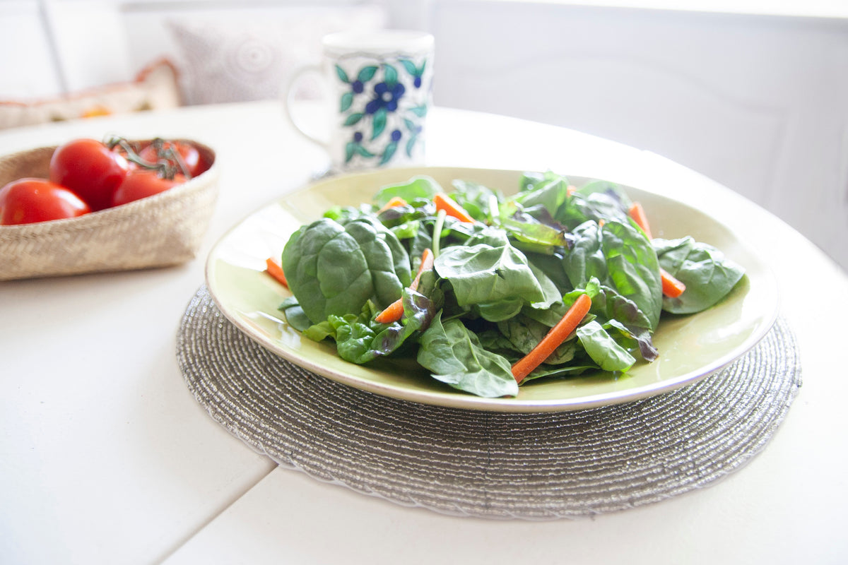 Dining table styled with a salad plate on a Rangeene silver glass beaded round placemat