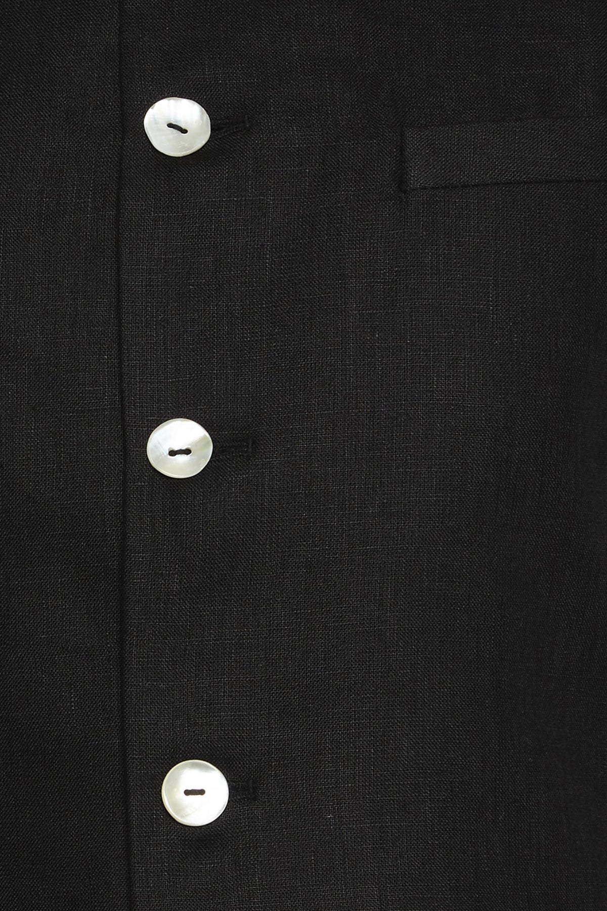 Fabric and stitching close-up of men's black cotton-linen Nehru jacket vest, highlighting premium wedding guest style.