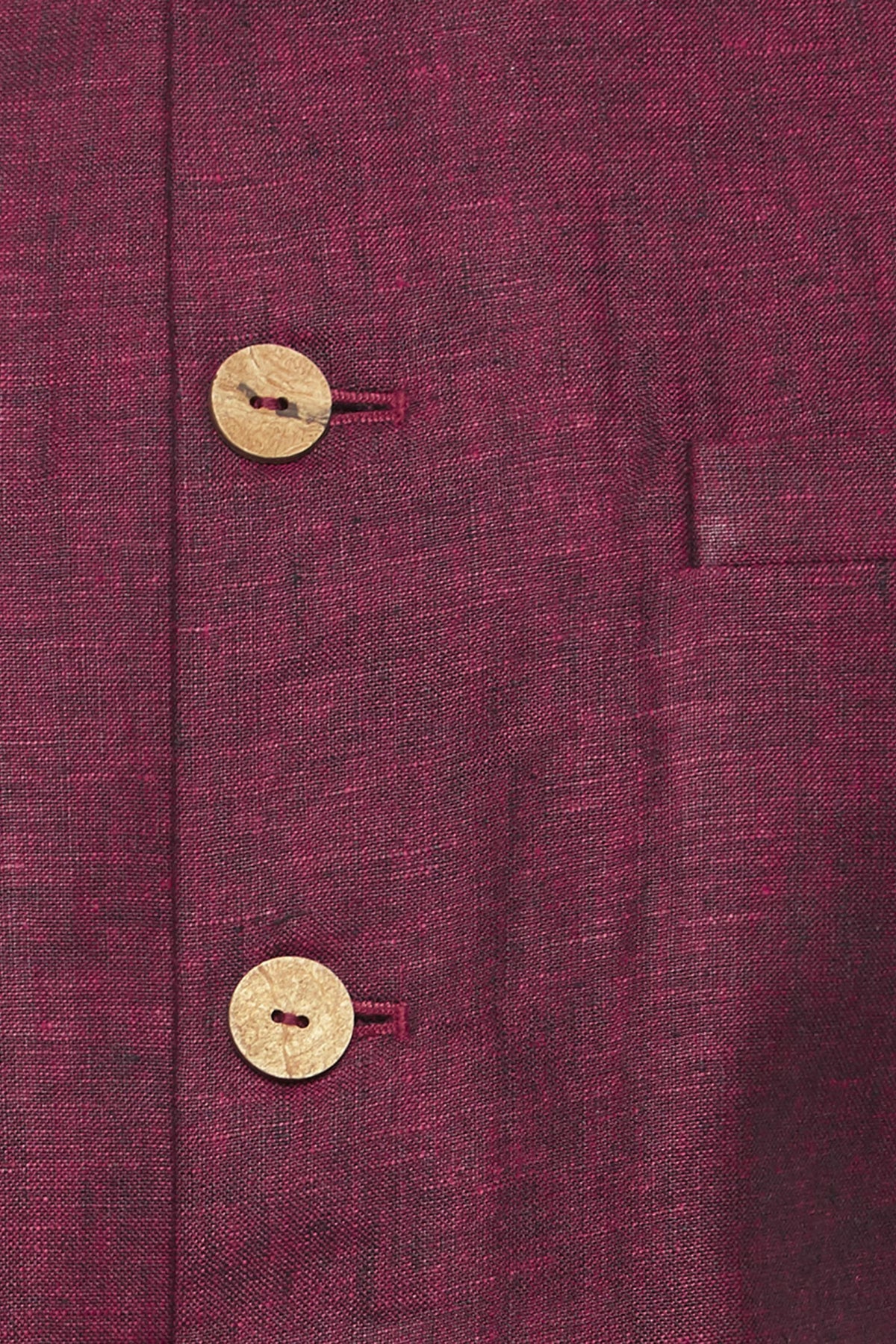 Fabric and stitching close-up of men's maroon Nehru jacket vest, highlighting vibrant festive wedding guest style.