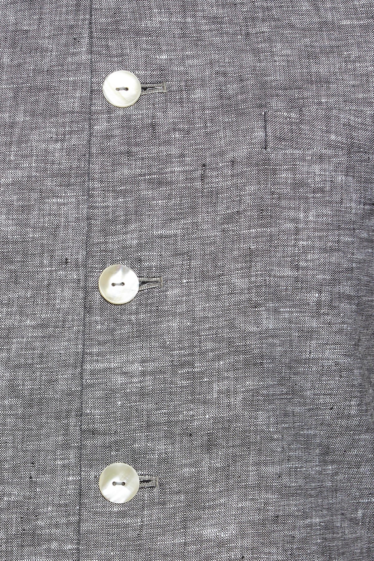 Fabric and stitching close-up of men's steel gray Nehru jacket vest, highlighting refined wedding guest style.