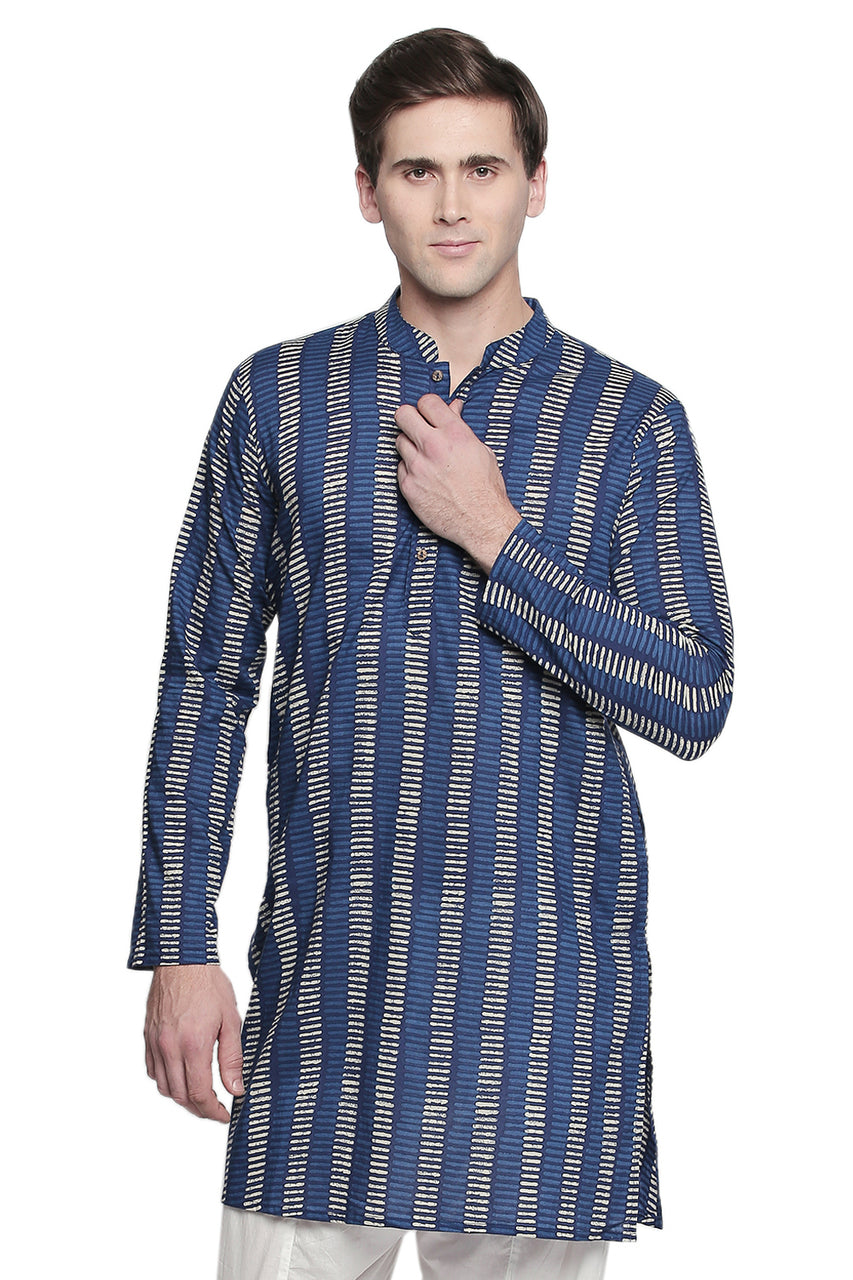 Front view of a model wearing In-Sattva's men's indigo block print cotton thigh-length kurta tunic, featuring a band collar, long sleeves, button placket and cream-colored block print pattern. One hand rests near the collar or placket.